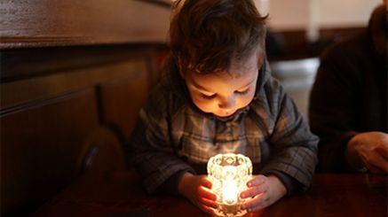Fotografia de uma criança segurando uma vela