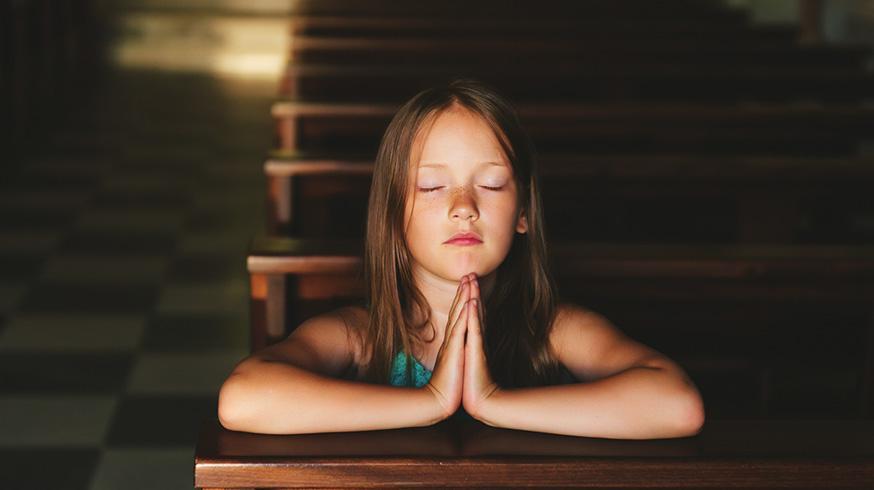 Fotografia de uma menina rezando