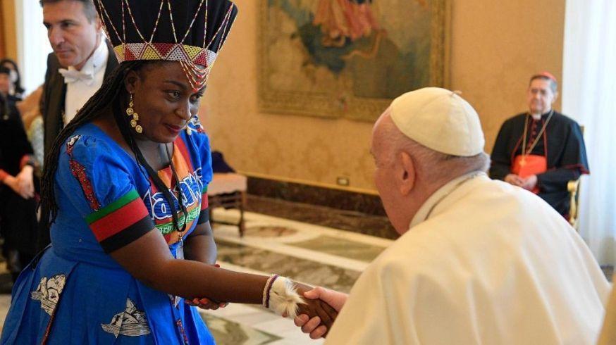 Fotografia de uma mulher negra com vestes africanas cumprimentando o Papa